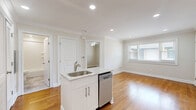 Located at 65 Cambridge Terrace in Hackensack, NJ, this thoughtfully designed two-bedroom residence makes excellent use of its single-floor layout. Warm hardwood flooring flows consistently throughout the entire space, complemented by crisp crown molding that lends a polished, cohesive aesthetic to every room.

The kitchen serves as a central highlight, featuring a large island with a marble-style countertop and an integrated sink and dishwasher. White shaker cabinetry lines the walls alongside a full suite of stainless steel appliances, including a gas range, built-in microwave, and refrigerator. A subway tile backsplash and recessed lighting complete the clean, modern look. A stacked washer and dryer unit is conveniently tucked within the kitchen area.

The primary bedroom offers a comfortable and well-proportioned retreat, with natural light provided by a window with blinds, crown molding, and a ceiling fan. It also features a dedicated walk-in closet with built-in shelving and hanging rods, offering generous storage. The second bedroom mirrors the same warm tones and natural light with its own window and crown molding details.

The open layout connecting the kitchen and living areas creates an airy, functional flow, making this residence a well-appointed and efficient home in a convenient Hackensack location.