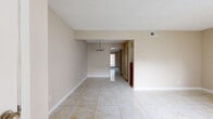 This well-organized single-floor residence offers a thoughtful layout comprising one bedroom, two bathrooms, a dining room, a kitchen, and a connecting hallway. Marble-look porcelain tile flooring runs throughout the entire space, lending a clean and cohesive aesthetic. The living and dining areas are open and connected, each accented by a modern chandelier and bathed in natural light from a front-facing window. Neutral beige walls and white baseboards complement the textured ceiling throughout. The dining area features built-in shelving with rich wood cabinetry, providing convenient storage. The galley-style kitchen is equipped with dark wood cabinetry, granite-look countertops, and stainless and black appliances including a refrigerator, range, microwave, and dishwasher. The primary bedroom is a comfortable, well-proportioned room with a ceiling fan and natural light from a side window, and includes access to multiple closets and doors leading to the bathrooms. Both bathrooms feature dark wood vanities with light stone countertops. The full bath includes a tub-shower combination, while the second bath offers a vanity with a framed mirror. The hallway efficiently connects all rooms, completing this compact yet functional floor plan.