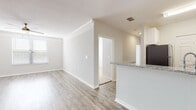 Located in the established Avalon Park East community of Orlando, Florida, this single-story residence offers a well-designed, open-concept floor plan with a neutral color palette and clean finishes throughout. The main living area features wood-look plank flooring and crown molding, lending a polished, cohesive feel to the space. A track lighting fixture adds functional illumination, while a louvered closet door provides convenient storage access. The living area flows naturally into the kitchen, which serves as a clear highlight of the home. White shaker-style cabinetry extends to the ceiling, maximizing storage, while granite countertops and a subway tile backsplash add texture and visual interest. Stainless steel appliances, including a refrigerator, range, microwave, and dishwasher, complete the kitchen. A peninsula with a granite overhang provides additional workspace and a natural divide between the kitchen and living areas. The bedrooms are carpeted for comfort and include windows fitted with horizontal blinds, allowing for natural light and privacy. The bathrooms feature wood-look vinyl flooring, white cabinetry with granite countertops, large mirrors, and a tub-shower combination, maintaining the home's consistent, modern aesthetic throughout.