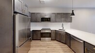 Located on Farmington Avenue in West Hartford, CT, this thoughtfully designed one-bedroom, one-bathroom unit delivers a modern living experience with high-quality finishes throughout. The open-concept kitchen is a standout feature, showcasing rich dark gray shaker-style cabinetry with gold hardware, sleek white quartz countertops, a white subway tile backsplash, and a full suite of stainless steel appliances. Stylish black pendant lighting adds a contemporary edge, while light hardwood flooring grounds the space warmly. A generous kitchen island provides additional prep space and casual seating. The spacious bedroom is carpeted for comfort and features a large double closet with crisp white paneled doors and black hardware, offering ample storage. A window brings in natural light with views of the surrounding neighborhood. The bathroom is elegantly finished with large-format gray floor tiles, a soaking tub with dramatic dark and marble-style tile surround, a dark wood vanity with a white countertop, and a well-lit mirror. A connecting hallway ties the layout together efficiently. The unit combines contemporary design with functional living in a desirable West Hartford location.