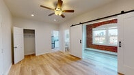 Located at 200 S Kenmore Ave in the heart of Los Angeles' Koreatown neighborhood, this single-floor unit has been thoughtfully renovated with a clean, modern aesthetic. Light wood-style flooring runs throughout, creating a warm and cohesive feel across all areas of the space.

The main living area is open and airy, featuring recessed lighting and a ceiling fan overhead. A standout design element is the sliding barn door that leads to a sun-filled nook defined by a charming exposed red brick accent wall and large windows offering views of the surrounding Los Angeles cityscape — flooding the space with natural light.

The kitchen is well-appointed with white shaker-style cabinetry, grey quartz countertops, a stainless steel sink with a modern gooseneck faucet, and a stainless steel refrigerator. Ample counter space and generous cabinet storage make it both functional and visually appealing.

A dedicated closet provides convenient storage off the main living area. The bathroom is elegantly finished with floor-to-ceiling marble-look tile surrounding a full soaking tub and shower combination, complemented by a white vanity and wood-look tile flooring that ties seamlessly into the rest of the unit.

The overall ambiance is bright, clean, and contemporary, with thoughtful details that blend modern finishes with character-rich architectural elements.