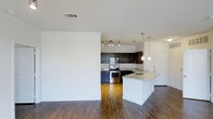 Located in Frisco, this single-floor residence offers a thoughtfully designed open-concept layout that seamlessly connects the living and kitchen areas. The kitchen is a standout feature, showcasing dark espresso cabinetry that contrasts beautifully against light granite countertops. Stainless steel appliances, including a range and built-in microwave, add a contemporary touch, while a peninsula with a built-in sink and pendant lighting above provides both additional prep space and a casual dining option. Track lighting illuminates the kitchen workspace, ensuring excellent visibility throughout. Rich hardwood flooring extends across the entire living and kitchen space, lending warmth and cohesion to the interior. Crown molding along the upper walls adds an elegant architectural detail, enhancing the overall sense of quality and finish. The open floor plan creates a natural flow between spaces, making the residence feel expansive and inviting. Clean white walls and neutral tones throughout the space provide a versatile backdrop for a variety of décor styles. This well-appointed Frisco residence combines modern design elements with functional living spaces, making it an ideal setting for everyday comfort and entertaining alike.