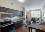 Located at 2263 S Douglas Rd in Miami, FL, this well-designed single-floor unit offers a cohesive and functional layout that seamlessly connects the main living areas. The open-plan kitchen and living space is a standout feature, anchored by a sleek kitchen equipped with dark espresso cabinetry, granite countertops, a white subway tile backsplash, and a full suite of stainless steel appliances including a refrigerator, electric range, built-in microwave, and dishwasher. Wood-look flooring runs throughout the kitchen and living areas, adding warmth and visual continuity. The living area is bright and inviting, benefiting from a large window that draws in natural light and provides views of the surrounding neighborhood. The bedroom is a calm retreat, finished with plush carpeting, soft neutral tones, and warm ambient lighting. The bathroom continues the design language of the unit with granite countertops, dark cabinetry, a single-basin sink, and light tile flooring. A closet with a rod and open shelving provides convenient storage directly adjacent to the bathroom. Overall, the unit presents a modern, cohesive aesthetic with quality finishes throughout, ideally situated in the vibrant Coral Way neighborhood of Miami.