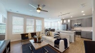 This single-story residence is thoughtfully designed with an open-concept layout that seamlessly connects the living, dining, and kitchen areas. The living room features warm hardwood-style flooring, a ceiling fan, and a bank of large windows dressed with horizontal blinds, allowing generous natural light to fill the space. A dedicated dining area is positioned within a windowed nook, accommodating a full dining set surrounded by multiple large windows that provide outdoor views.

The kitchen is a standout feature, outfitted with slate-gray shaker-style cabinetry, light granite countertops, stainless steel appliances including a refrigerator and microwave, a subway tile backsplash, and pendant lighting above a kitchen island with bar seating. Under-cabinet lighting enhances both functionality and ambiance.

The bedrooms are carpeted and well-lit, each equipped with ceiling fans and windows that invite natural light. The primary bathroom offers a dual-sink vanity with granite countertops, gray cabinetry with brushed nickel hardware, large mirrors, and direct access to a walk-in closet. Throughout, the neutral color palette and consistent finishes create a cohesive, modern aesthetic.