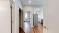 Located at 6804 Tides Rd, Unit 4G in Rockaway, New York, this well-appointed single-floor residence offers a clean, modern aesthetic throughout. Warm hardwood-style flooring runs continuously across the living areas, bedrooms, and hallways, creating a cohesive and inviting atmosphere.

The kitchen is a standout feature, designed in a galley-style layout with crisp white cabinetry extending to the ceiling, stainless steel appliances including a refrigerator, microwave, and dishwasher, and a generous peninsula countertop with an undermount sink. Stylish pendant lighting hangs above the peninsula, adding a contemporary touch to the space.

The open living area is bright and airy, benefiting from natural light through well-placed windows and recessed ceiling lighting. Each bedroom is comfortably proportioned, featuring windows with exterior views, roller shades, and individual PTAC heating and cooling units for personalized climate control.

The bathrooms are tastefully finished, showcasing white subway tile with a distinctive teal accent stripe, a glass-enclosed walk-in shower, a soaking tub, and a white vanity with ample storage. The neutral color palette and clean lines throughout the unit contribute to a fresh, move-in-ready environment.