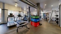 This state-of-the-art fitness facility, located at 550 N 5th Ave in Tucson, AZ, offers a comprehensive workout experience within its 1240 square foot space. The gym's design seamlessly blends functionality with industrial chic, featuring exposed ductwork and support columns that add character to the space. Large windows allow abundant natural light to flood the area, creating an energizing atmosphere.

The layout is thoughtfully arranged to accommodate various exercise preferences. Multiple treadmills and cardio machines line the windowed area, allowing users to enjoy outdoor views during their workouts. The center of the room houses a versatile array of strength training equipment, including weight machines and free weights. Colorful, stackable plyo boxes add a pop of vibrancy to the space and offer options for functional training.

The facility's attention to detail is evident in its modern amenities, including wall-mounted TVs for entertainment, ceiling fans for comfort, and strategically placed lighting. The polished concrete flooring not only complements the industrial aesthetic but also provides a durable surface for heavy equipment. With its well-rounded selection of exercise options and inviting ambiance, this fitness center caters to a wide range of fitness enthusiasts and goals.
