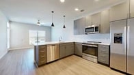 This 1-bedroom, 1-bathroom residence is thoughtfully laid out across a single floor, offering a clean and modern living experience. The open-concept kitchen is a standout feature, outfitted with sleek gray cabinetry extending to the ceiling, white quartz countertops, a subway tile backsplash, and a full suite of stainless steel appliances including a side-by-side refrigerator with ice maker, electric range, built-in microwave, and dishwasher. Stylish pendant lighting accents the kitchen peninsula, which flows naturally into the living area. The living room is bright and welcoming, featuring light wood-look flooring, neutral walls, and a glass-paneled door that invites natural light and provides outdoor access. The generously sized primary bedroom is finished with plush carpeting, soft neutral tones, a ceiling fan, and a sizable window with blinds that fills the room with daylight. A dedicated closet provides ample storage. Throughout the unit, clean white trim, recessed lighting, and a consistent neutral color palette create a cohesive, contemporary ambiance suited for comfortable everyday living.