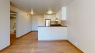 Located at 1801 Aviation Way in Redondo Beach, CA, this one-bedroom, one-bathroom apartment offers a well-designed single-floor layout that makes efficient use of its space. The open-concept living and kitchen area features light wood-style flooring that creates a warm, cohesive feel throughout. The kitchen is equipped with stainless steel appliances, including a refrigerator, electric range, and dishwasher, complemented by crisp white cabinetry with ample storage and dark countertops. A peninsula-style counter separates the kitchen from the living area, providing additional prep space and a casual dining option. The living area is bright and open, benefiting from the kitchen's flush-mount lighting and a clean, neutral color palette. The bedroom is carpeted for added comfort and features a generously sized window that invites natural light and offers a pleasant view of surrounding greenery. The bathroom is finished with light wood-style flooring and includes a full tub and shower combination with grab bar support, a white vanity with under-sink storage, a wall-mounted medicine cabinet, and overhead vanity lighting. The overall design is clean and functional, with neutral tones throughout that provide a versatile backdrop for a variety of furnishing styles.