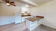 Located at 2545 Fulton Ave in the Arden-Arcade neighborhood of Sacramento, CA, this one-bedroom, one-bathroom unit offers a practical and comfortable single-floor layout. The open-concept living and kitchen area creates an inviting common space, where light wood-style flooring transitions seamlessly from the kitchen into the carpeted living area. The kitchen is well-appointed with white cabinetry, granite-style countertops, a gas range, a full-size refrigerator, and a peninsula with built-in open shelving — ideal for both storage and casual dining. A ceiling fan overhead adds to the comfort of the space. The living area is bright and open, benefiting from natural light and a built-in shelving unit that provides additional storage. The bedroom is a comfortable size, featuring plush carpet, a ceiling fan, a window with exterior views, and access to a dedicated closet. The bathroom is cleanly designed with wood-style flooring, a pedestal sink, a mirrored medicine cabinet, and a full bathtub. Warm, neutral tones throughout the unit create a cohesive and calm ambiance, making this an efficient and functional home.