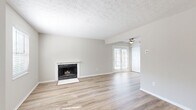 This two-story home in Columbus, Ohio offers a practical and comfortable layout spread across two floors. The main level features a bright living room with light-toned luxury vinyl plank flooring, a textured ceiling, a wood-burning fireplace with a tile hearth, and French doors that invite natural light and provide outdoor access. A ceiling fan adds to the room's functionality. The kitchen is well-appointed with rich dark cabinetry, light stone-look countertops, a mosaic tile backsplash, and a full suite of stainless steel appliances including a gas range, built-in microwave, and dishwasher. A hallway with closet storage connects the main living areas. The staircase leads to the upper level, where two carpeted bedrooms offer a comfortable retreat. The spacious primary bedroom features a large closet and a window for natural light. The second bedroom is generously sized with its own window. The full bathroom is clean and functional, complete with a tub-shower combination, a dark-cabinetry vanity with a white countertop, and a mirrored medicine cabinet. Neutral gray walls and textured ceilings are consistent throughout, giving the home a cohesive, move-in-ready appearance.
