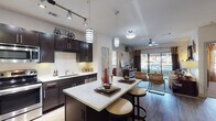 Located at 444 W Commerce St in Dallas, Texas, this single-story residence offers a thoughtfully designed layout with contemporary finishes and a cohesive modern aesthetic throughout. The gourmet kitchen is a standout feature, boasting rich dark cabinetry, granite countertops, a full suite of stainless steel appliances including a refrigerator, range, microwave, and dishwasher, plus a tile backsplash and under-cabinet lighting. A generous island with bar seating and stylish pendant lighting makes it ideal for both cooking and entertaining. The kitchen flows seamlessly into the open living area, which features wood-style flooring, a ceiling fan, and sliding glass doors that open to a private balcony with outdoor views, flooding the space with natural light. The two bedrooms each offer plush carpeting, large windows, and ceiling fans. One bedroom features a bold accent wall and wood-paneled headboard, while the other is accented with decorative wall art and warm tones. Each bedroom connects to a well-appointed bathroom with dark vanity cabinetry, granite countertops, and a glass-enclosed tiled shower. Spacious walk-in closets with built-in shelving and hanging rods provide generous storage. Wood-style flooring extends through the hallways, tying the entire space together with a polished, modern feel.