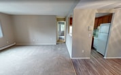Located at 145 Essex Rd in Warwick, Rhode Island, this single-floor apartment offers 860 square feet of practical living space across two bedrooms and a combined kitchen and living room. The kitchen features warm honey-toned wood cabinetry, granite-look countertops, a breakfast bar, and white appliances including a range, dishwasher, and refrigerator, all finished with easy-to-clean laminate wood flooring. The open layout connects the kitchen directly to the living area, creating an efficient and sociable flow. Both bedrooms are carpeted in neutral tones and painted in soft greige, providing a calm, versatile backdrop. The primary bedroom measures 160 square feet and includes a wall-mounted air conditioning unit and baseboard heating. The second bedroom also features baseboard heating and a window with outdoor views of surrounding greenery. Each bedroom benefits from its own dedicated closet, offering organized storage. Throughout the unit, consistent neutral wall tones, white trim, and carpet create a cohesive, move-in-ready aesthetic. Wall-unit air conditioning and baseboard heating are present in multiple rooms, ensuring year-round climate control across the entire apartment.