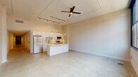 Located in the heart of downtown Akron at 530 S Main St, this thoughtfully designed 2-bedroom, 3-bathroom loft-style residence blends industrial character with modern finishes across a single floor. The open-concept living, dining, and kitchen area serves as the centerpiece, boasting soaring ceilings with exposed infrastructure, polished concrete floors, and striking large-pane factory-style windows that flood the space with natural light and frame urban views of the surrounding brick architecture. The kitchen is outfitted with crisp white shaker cabinetry, white quartz countertops, a classic subway tile backsplash, stainless steel appliances, a deep undermount sink with a matte black faucet, and a generous island — all illuminated by pendant lighting and adjustable track lighting overhead. A long hallway connects the private quarters, where both bedrooms feature plush carpeting and ceiling fans. Each bedroom includes dedicated closet space. The three bathrooms are finished with white vanities, quartz countertops, and matte black hardware; one features a sliding glass walk-in shower, while another offers a full soaking tub and shower combo. Three closets provide ample storage throughout. The cohesive use of matte black accents against neutral tones gives the entire residence a refined, contemporary urban aesthetic.