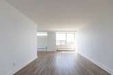 Located at 35 St Dennis Dr in Toronto's Don Mills neighbourhood, this 2-bedroom, 1-bathroom unit offers a well-organized, single-floor layout designed for comfortable everyday living. The interior is finished with light-toned hardwood flooring throughout, crisp white walls, and clean baseboards that contribute to a bright, cohesive aesthetic.

The spacious living room is a standout feature, anchored by floor-to-ceiling windows that flood the space with natural light and frame views of the surrounding treetops and cityscape. A dedicated hallway connects the main living areas to the private bedrooms, providing a clear and functional flow. The primary bedroom is generously sized, featuring a large window with an elevated city view and a closet. The second bedroom also benefits from natural light through its own window overlooking the neighbourhood.

The kitchen is equipped with modern cabinetry and countertops, and features a wide window wall that brings in additional light and outdoor views. The bathroom is neatly finished with subway tile, a modern vanity with under-sink storage, a mirrored medicine cabinet, and contemporary light fixtures. Throughout the unit, the design prioritizes simplicity, light, and practicality, making it a well-appointed home in a central Toronto location.