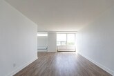 Located at 35 St Dennis Dr in Toronto's Don Mills neighbourhood, this 2-bedroom, 1-bathroom unit offers a well-organized, single-floor layout designed for comfortable everyday living. The interior is finished with light-toned hardwood flooring throughout, crisp white walls, and clean baseboards that contribute to a bright, cohesive aesthetic.

The spacious living room is a standout feature, anchored by floor-to-ceiling windows that flood the space with natural light and frame views of the surrounding treetops and cityscape. A dedicated hallway connects the main living areas to the private bedrooms, providing a clear and functional flow. The primary bedroom is generously sized, featuring a large window with an elevated city view and a closet. The second bedroom also benefits from natural light through its own window overlooking the neighbourhood.

The kitchen is equipped with modern cabinetry and countertops, and features a wide window wall that brings in additional light and outdoor views. The bathroom is neatly finished with subway tile, a modern vanity with under-sink storage, a mirrored medicine cabinet, and contemporary light fixtures. Throughout the unit, the design prioritizes simplicity, light, and practicality, making it a well-appointed home in a central Toronto location.