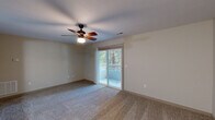 Located at 3157-27 Berry Ln in Roanoke, VA, this single-floor, 2-bedroom, 2-bathroom home offers a well-organized layout designed for comfortable living. The kitchen is a standout feature, equipped with rich dark wood cabinetry, granite-style countertops, a full suite of stainless steel appliances including a refrigerator, range, microwave, and dishwasher, and track lighting overhead — all set atop durable hardwood-style flooring. The hallway area connects the main spaces seamlessly and includes an in-unit washer and dryer alongside an electrical panel, adding everyday convenience. The generously sized primary bedroom features soft carpet flooring, a ceiling fan with light fixture, and sliding glass doors that open to a private balcony with outdoor views of surrounding greenery. The second bedroom is carpeted as well, with a six-panel door and clean neutral walls. Both bathrooms are functional and well-appointed, with one featuring a full tub/shower combo and chrome fixtures. The living room continues the carpeted, neutral aesthetic, complemented by its own ceiling fan and natural light. Throughout the home, a consistent neutral color palette and practical finishes create a clean, move-in-ready environment.