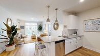 This thoughtfully designed 2-bedroom, 2-bathroom single-floor residence offers a bright, open-concept layout with a coastal aesthetic that flows seamlessly from room to room. Warm hardwood-style flooring extends throughout, tying together a cohesive and inviting atmosphere.

The kitchen is a functional centerpiece, featuring white shaker cabinetry, granite countertops, a subway tile backsplash, and a full suite of stainless steel appliances. A peninsula with bar seating and pendant lighting creates an ideal space for casual dining and entertaining. The adjacent living room is bathed in natural light from large windows and a sliding glass door, opening the space to outdoor views. A dedicated dining area with a wall-mounted mirror adds depth and refinement.

The spacious primary bedroom includes a private en-suite bathroom with a walk-in glass shower finished in classic white subway tile, granite vanity countertops, and hardwood-style flooring. The second bedroom is generously sized, featuring a bright window, ample natural light, and access to a second full bathroom with a soaking tub and tiled surround. Both bathrooms maintain a clean, neutral palette. A dedicated closet provides additional storage. The home's coastal-inspired décor and light-filled interiors create a serene, comfortable living environment.