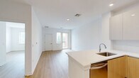 This thoughtfully designed one-bedroom, one-bathroom residence at 2050 Central Road in Fort Lee, New Jersey offers a clean, modern aesthetic throughout. Light-toned hardwood-style flooring flows seamlessly across the entire unit, complementing the bright white walls and creating a warm, contemporary atmosphere.

The open-concept kitchen and living area serves as the heart of the home. The kitchen is well-appointed with two-tone cabinetry — combining high-gloss white upper cabinets with natural wood lower cabinets — paired with a crisp white countertop and stainless steel appliances, including a gas range, built-in microwave, and full-size refrigerator. A deep undermount sink adds to the kitchen's functional design.

The living area flows naturally from the kitchen, providing a versatile and open layout. The spacious bedroom features a sliding glass door leading to a private balcony, along with a window offering views of the surrounding Fort Lee cityscape, filling the room with natural light. An additional closet provides convenient storage.

The bathroom is finished with large-format light tiles, a clean white subway-tiled shower, and a wood-accented vanity. A standout feature is the in-unit stacked washer and dryer, adding everyday convenience. The overall ambiance is bright, minimalist, and move-in ready.