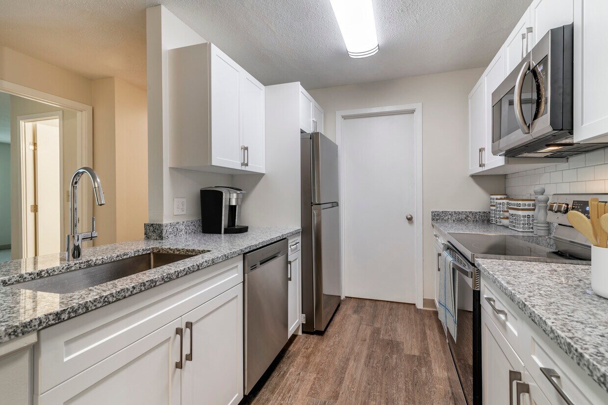 Paquete renovado I cocina con electrodomésticos de acero inoxidable, encimeras de granito moteado gris, gabinetes de color blanco, placa para salpicaduras de azulejos blancos, y pisos de superficie dura - eaves Burlington