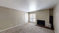 Located at 9821 Summerwood Cir in Dallas, TX, this one-bedroom, one-bathroom residence offers a well-organized, single-floor layout with a comfortable and functional design throughout. The living room serves as the heart of the home, featuring plush wall-to-wall carpeting, neutral beige walls, a textured ceiling, and a standout wood-burning fireplace with a dark brick hearth — an inviting focal point for relaxing evenings. A window with blinds allows natural light to fill the space. The kitchen is efficiently designed with warm wood cabinetry, a dark granite-style countertop peninsula that doubles as a breakfast bar, under-cabinet lighting, a stainless steel refrigerator, and a sink with ample workspace. Wood-look flooring in the kitchen provides a clean contrast to the carpeted areas. The bedroom is a comfortable retreat with carpeted flooring, a window with blinds offering natural light, and neutral tones throughout. Two closets provide generous storage options. The bathroom features light wood-look tile flooring, a combined shower and bathtub, and a clean, straightforward design. Overall, the space presents a practical and cozy living environment with consistent neutral tones and functional details throughout.