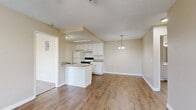 Located at 501 Greenfield Drive in El Cajon, California, this two-bedroom, one-bathroom residence offers a practical and well-appointed single-floor layout. The open-concept kitchen and living area form the heart of the home, featuring warm hardwood-style flooring, a peninsula with granite-style countertops, white cabinetry, and a range with overhead ventilation. A pendant chandelier adds a decorative touch, while the adjoining living space benefits from a ceiling fan and a window that invites natural light and outdoor views.

The primary bedroom is generously sized and includes plush carpet, a ceiling fan, and sliding glass doors opening to a private balcony with views of the surrounding neighborhood. A spacious walk-in closet with built-in shelving and hanging rods provides ample storage. The second bedroom also features carpet, a window with blinds, and a wall-mounted air conditioning unit. Both rooms share a full bathroom finished with hardwood-style flooring, a granite-style vanity, and a separate toilet area. Throughout the residence, neutral warm-beige walls and textured ceilings create a cohesive, comfortable ambiance suited for everyday living.