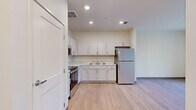 This 2-bedroom, 1-bathroom unit in Detroit, MI (48202) offers a clean, modern design across a single floor. The kitchen is well-appointed with white shaker-style cabinetry, marble-look countertops, a double-basin sink, and a full suite of stainless steel appliances including a refrigerator, range with oven, and built-in microwave. Light wood-style flooring runs consistently throughout the entire unit, lending a cohesive and contemporary feel. Recessed lighting illuminates the kitchen and adjacent hallway areas. The living room is bright and open, featuring large floor-to-ceiling windows that frame outdoor views of the surrounding Detroit neighborhood, allowing generous natural light to fill the space. Both bedrooms feature the same light wood flooring, neutral walls, and clean-lined panel doors. The primary bedroom offers a comfortable footprint suitable for standard furnishings. The second bedroom also benefits from a large window with exterior views. The bathroom includes a walk-in shower with a curtain rod, a white surround, and a vanity with matching marble-look countertops. A connecting hallway provides practical flow between all rooms, completing this efficiently designed and move-in ready residential unit.