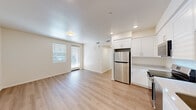 Located at 1385 W College Ave in Santa Rosa, CA, this single-floor unit offers a clean, modern design across three bedrooms and one bathroom. The open-concept kitchen and living area forms the heart of the home, featuring light hardwood-style flooring, recessed lighting, and a neutral white color palette that creates a bright, airy atmosphere. A door provides direct access to the exterior, allowing natural light to flow into the shared living space. The kitchen is well-appointed with white shaker-style cabinetry, light countertops, a stainless steel refrigerator, range, over-the-range microwave, and dishwasher, offering a full complement of modern appliances. The three bedrooms are finished consistently with the same light flooring and warm neutral walls, each featuring windows with blinds that provide natural light and privacy. The primary bedroom is a comfortable, well-proportioned space. The bathroom is finished with a white vanity, light countertop, a large mirror, a bathtub/shower combination, and matching hardwood-style flooring. The building exterior presents a contemporary multi-story facade with a clean, modern aesthetic and on-site parking, situated in a convenient Santa Rosa location.