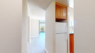 Located at 1160 Lincoln Ave in Walnut Creek, CA, this two-bedroom, two-bathroom residence offers a well-designed single-level layout with a variety of distinctive architectural features. The living area is the standout space, boasting a soaring vaulted ceiling clad in warm wood paneling, floor-to-ceiling windows, and sliding glass doors that open to a private balcony overlooking lush, tree-lined views. Built-in glass shelving adds a functional accent, while light hardwood flooring and a ceiling fan complete the bright, airy atmosphere. The kitchen is well-appointed with rich honey-toned wood cabinetry, dark granite countertops, and white appliances including a range, dishwasher, and refrigerator. A breakfast bar separates the kitchen from the living area, creating an open and connected feel. Both bedrooms feature plush carpeting and generous closet space, including mirrored sliding-door closets. Large windows in each bedroom invite natural light and offer peaceful outdoor views. The two bathrooms are finished with granite-topped vanities and warm wood cabinetry, with one bathroom featuring a marble-tiled shower and tub combination. Hallways connect the rooms efficiently, and two dedicated closets provide ample storage throughout.