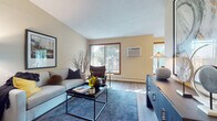 This single-floor residence offers a thoughtfully designed layout that balances comfort and functionality across its key living spaces. The living room serves as the heart of the home, featuring warm beige walls, hardwood-style flooring, a textured ceiling, and large wood-framed windows that invite generous natural light and views of mature surrounding trees. A wall-mounted air conditioning unit and baseboard heating provide year-round climate control.

The galley-style kitchen is efficiently arranged with rich wood cabinetry, granite-style countertops, and stainless steel appliances including a refrigerator and dishwasher. It opens directly toward the dining area, which is brightened by a large picture window overlooking lush greenery, creating an airy and pleasant space for meals.

The bedroom is a serene retreat, carpeted for warmth and comfort, with mirrored sliding closet doors that enhance the sense of space. A window allows natural light to filter in, complementing the calm, neutral palette throughout.

The full bathroom is cleanly finished with tile flooring, a tub-shower combination with tiled surround, a vanity with wood cabinetry, and classic white fixtures. Throughout the residence, cohesive warm tones and hardwood-style flooring in the main areas create an inviting, unified aesthetic.