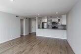 Located in the desirable Los Feliz neighborhood of Los Angeles, this single-floor residence at 1840 N Kenmore Ave offers a clean, modern aesthetic throughout. Light wood-tone flooring spans the entire unit, creating a cohesive and airy feel from room to room.

The open living area is generously proportioned, bathed in natural light streaming through large floor-to-ceiling windows dressed with vertical blinds. Recessed lighting complements the bright, neutral palette of soft white and light gray walls, enhancing the sense of openness.

The kitchen is well-appointed with white shaker-style cabinetry, stone-look countertops, a tile mosaic backsplash, and a full suite of stainless steel appliances including a refrigerator, electric range, and microwave. A peninsula with an undermount sink provides additional prep space and a natural division between the kitchen and living areas. Glass-front upper cabinets add a refined touch.

The bedroom features recessed lighting, neutral walls, and large windows that invite natural light. The bathroom is cleanly finished with a full tub-shower combination, chrome fixtures, and wood-tone flooring that ties into the rest of the unit.

Overall, the space presents a bright, move-in ready interior with modern finishes in a prime Los Angeles location.