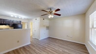 Located at 3551 Forestdale Dr in Burlington, NC, this one-bedroom, one-bathroom unit offers a practical and well-organized single-floor layout. Throughout the space, wood-look laminate flooring provides a clean, cohesive aesthetic, while neutral beige walls and white trim create a bright, open feel.

The combined kitchen and living area forms the heart of the unit. The kitchen features dark cabinetry with brushed hardware, light countertops, a stainless steel refrigerator, and a range, all arranged in an efficient galley-style configuration. The adjacent living area benefits from a ceiling fan with integrated lighting, a textured ceiling, and a sliding glass door fitted with vertical blinds that allows natural light and outdoor access.

The bedroom is a comfortable, well-proportioned room equipped with its own ceiling fan, a window with blinds for natural light, and direct access to a dedicated closet. The closet provides organized storage for the bedroom.

The bathroom is neatly appointed with dark wood cabinetry beneath a single vanity, a well-lit mirror, a tub-shower combination, and wood-look flooring that ties in with the rest of the unit.

Additional features include HVAC vents throughout and a front entry door accessed from the living area, making this a functional and straightforward unit in Burlington, NC.