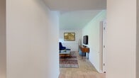Located at 5353 Harpers Farm Rd in Columbia, Maryland, this single-floor home showcases a cohesive mid-century modern aesthetic throughout its well-appointed layout. The living room is a standout space, featuring elegant parquet hardwood flooring, crown molding with a classic chair rail, and abundant natural light. The room comfortably accommodates a conversational seating arrangement and an entertainment area, creating a warm and inviting atmosphere.

The kitchen is thoughtfully designed with rich cherry wood cabinetry, granite countertops, a subway tile backsplash, and stainless steel gas range. A stacked washer and dryer unit is conveniently integrated into the kitchen area, and a bright dining nook with a window view completes the space.

The primary bedroom offers a serene retreat with plush carpet flooring, generous double closets, and a warm, neutral palette. A second bedroom serves well as a quiet home office, featuring carpet flooring, a large window with natural light, and ample space for a desk and shelving. An additional bedroom provides comfortable accommodations with soft carpeting and vibrant décor accents.

The bathroom is clean and functional, featuring a tub-shower combination with white tile surround, a granite-topped vanity with cherry wood cabinetry, and a round mirror. Throughout, the home maintains a bright, neutral tone that complements its mid-century character.