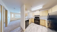 Located at 14002 Linden Ave N in Seattle, WA, this one-bedroom, one-bathroom unit offers a practical and well-organized layout across a single floor. The kitchen is a standout feature, equipped with light maple cabinetry, ample counter space, and a full suite of black appliances including a gas range, dishwasher, and refrigerator. Light vinyl plank flooring runs throughout the kitchen, which also benefits from a skylight that brings in natural light. The kitchen opens toward the living area, which is finished with plush carpeting and a large window fitted with blinds, allowing in natural light and views of the surrounding building exteriors. A baseboard heating unit runs beneath the window, ensuring year-round comfort. The bedroom is a well-proportioned, carpeted space featuring a full-width sliding closet with light wood panel doors, offering generous storage. The bathroom is accessibility-conscious, featuring grab bars, a tub-shower combo, a wood-toned vanity with a wide countertop and mirror, and easy-clean vinyl plank flooring. Overall, the unit presents a clean, neutral palette with warm wood tones throughout, creating a simple and functional living environment.