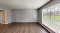 Located in Baton Rouge, LA, this well-appointed 2-bedroom, 2-bathroom residence offers a practical and comfortable single-floor layout. The living room welcomes you with rich hardwood-style flooring, neutral gray walls, a textured ceiling, and a large window fitted with blinds that invites generous natural light and outdoor views of the surrounding greenery. The kitchen is efficiently designed with ample white cabinetry, white countertops, black appliances including an electric range, dishwasher, and refrigerator, track lighting overhead, and hardwood-style flooring. A notable convenience is the in-unit stacked washer and dryer located within the kitchen area. Both bedrooms feature plush carpeting, ceiling fans with light fixtures, and closet space. The spacious primary bedroom includes multiple closets and direct access to one of the two bathrooms. Each bathroom is outfitted with a tub-shower combination, tile wainscoting, and hardwood-style flooring. A connecting hallway ties the layout together cohesively. Throughout the unit, consistent neutral tones and textured ceilings contribute to a clean, functional living environment.
