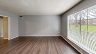 Located in Baton Rouge, LA, this well-appointed 2-bedroom, 2-bathroom residence offers a practical and comfortable single-floor layout. The living room welcomes you with rich hardwood-style flooring, neutral gray walls, a textured ceiling, and a large window fitted with blinds that invites generous natural light and outdoor views of the surrounding greenery. The kitchen is efficiently designed with ample white cabinetry, white countertops, black appliances including an electric range, dishwasher, and refrigerator, track lighting overhead, and hardwood-style flooring. A notable convenience is the in-unit stacked washer and dryer located within the kitchen area. Both bedrooms feature plush carpeting, ceiling fans with light fixtures, and closet space. The spacious primary bedroom includes multiple closets and direct access to one of the two bathrooms. Each bathroom is outfitted with a tub-shower combination, tile wainscoting, and hardwood-style flooring. A connecting hallway ties the layout together cohesively. Throughout the unit, consistent neutral tones and textured ceilings contribute to a clean, functional living environment.
