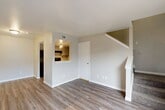 Located at 13100 Stonefield Dr in Houston, TX, this two-story home offers a well-organized layout spread across two floors. The main level features a combined living, dining, and kitchen area finished with light wood-look laminate flooring and neutral toned walls that create a bright, open atmosphere. A pass-through window connects the kitchen to the living area, providing an open feel while maintaining defined spaces. The kitchen is equipped with gray cabinetry, stone-look countertops, black appliances including a refrigerator and electric range, and track lighting overhead. Sliding glass doors off the living area open to a private patio, bringing in natural light and convenient outdoor access. A staircase with a classic white newel post leads to the upper level, where the spacious bedroom is carpeted and features a ceiling fan with light, a window with neighborhood views, and direct access to two closets and the full bathroom. The bathroom includes a tiled shower-tub combination. The overall design is clean and functional, with consistent neutral tones throughout both floors creating a cohesive and comfortable living environment.