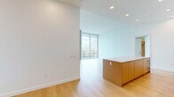 Located on the 20th floor at 525 Olive Street in San Diego's Bankers Hill, this contemporary high-rise residence offers an exceptional urban living experience with four bedrooms and three bathrooms spread across a thoughtfully designed single-level floor plan. Light hardwood flooring flows throughout, complementing the clean, modern aesthetic defined by crisp white walls and recessed lighting.

The open-concept kitchen and living area anchors the residence, featuring a large waterfall-edge island, sleek flat-panel cabinetry in warm wood and white finishes, stainless steel appliances including a built-in microwave, and a gas range. Floor-to-ceiling glass walls in the living area lead to a spacious balcony with glass-panel railings, offering sweeping views of Balboa Park, the San Diego cityscape, and distant mountains.

The generously sized primary bedroom includes an expansive walk-in closet with built-in shelving and hanging rods. Additional bedrooms feature the same hardwood flooring, large windows, and access to remarkable city views. One bedroom features a sliding barn-style door, adding a modern architectural detail. The bathrooms are finished with neutral herringbone tile, soaking tubs, and brushed gold fixtures. An in-unit laundry area with full-size washer rounds out the practical amenities of this elevated urban residence.