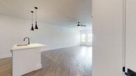 This well-designed single-floor residence offers a thoughtful layout that maximizes both comfort and functionality. The open-concept kitchen and living area serves as the heart of the home, featuring sleek white cabinetry, stainless steel appliances, recessed lighting, and a central island with an undermount sink accented by striking black pendant lights overhead. The kitchen flows seamlessly into a spacious living area with warm hardwood-style flooring, a ceiling fan, and large windows that invite abundant natural light and views of the surrounding neighborhood.

The generously sized primary bedroom continues the clean aesthetic with light wood-tone flooring, a ceiling fan, and direct access to two closets — including a walk-in closet outfitted with full wire shelving systems for ample organized storage. A dedicated laundry area adds everyday convenience.

The bathroom is finished in a contemporary style, showcasing a white shaker-style vanity with quartz countertops, black hardware accents, a bold framed mirror, and a well-lit vanity bar. Consistent hardwood-style flooring runs throughout, tying the entire space together with a cohesive, modern palette of crisp whites and neutral tones that create a clean, bright, and inviting atmosphere.