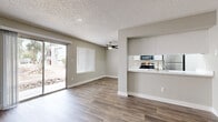 Located in Phoenix, AZ, this 2-bedroom, 2-bathroom single-floor unit offers a clean, modern aesthetic throughout. Wood-look plank flooring runs continuously across the open-concept living and dining area, which is anchored by a ceiling fan and abundant natural light from large windows and a sliding glass door that opens to an outdoor patio with desert landscaping views.

The kitchen is designed for functionality and style, featuring white shaker cabinetry with brushed gold hardware, quartz countertops, a stainless steel undermount sink, and a full suite of stainless steel appliances including a refrigerator, range, and over-the-range microwave. A skylight brightens the kitchen interior. A pass-through opening connects the kitchen seamlessly to the living area.

Both bedrooms continue the wood-look flooring and neutral color palette, offering a calm and versatile environment. The primary bedroom provides a comfortable footprint and leads to a well-appointed bathroom featuring white cabinetry, quartz countertops, and a tub-shower combination. Each bathroom is finished with brushed nickel fixtures and mirrors. Two dedicated closets provide organized storage throughout the unit. Textured ceilings and clean white trim complete the cohesive, updated interior design.
