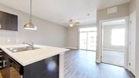 Located at 1000 S Broadway in Denver's vibrant Broadway corridor, this single-floor residence offers a thoughtfully designed open-concept layout with modern finishes throughout. The living area features durable hardwood-style flooring, a ceiling fan, and large sliding glass doors that flood the space with natural light while providing direct access to a private balcony with urban views. The kitchen is a standout feature, anchored by a sleek white quartz peninsula that separates it from the living area. Dark espresso cabinetry provides generous storage, complemented by stainless steel appliances including a refrigerator, electric range, and over-the-range microwave. A classic white subway tile backsplash adds a clean, contemporary touch. Pendant lighting and a track light fixture illuminate the kitchen workspace effectively. The bedroom areas offer plush carpeting for comfort, ample natural light through large windows, and access to a private entry door. The bathroom is finished with dark espresso vanity cabinetry, white quartz countertops, a full soaking tub, and hardwood-style flooring, maintaining design consistency throughout. Neutral warm-gray walls and clean white trim create a cohesive, modern aesthetic across the entire space.
