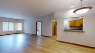 Located on Watertown Road in Waukesha, Wisconsin, this well-appointed two-bedroom, three-bathroom single-floor residence offers a thoughtfully designed layout with consistent light hardwood flooring throughout. The open-concept living and dining area provides a generous, airy feel, flowing naturally toward the kitchen. The kitchen is equipped with warm oak cabinetry, granite countertops, stainless steel appliances including an electric range with over-the-range microwave, and a convenient pass-through counter that connects to the main living space. Two well-sized bedrooms offer natural light through large windows with outdoor views, ceiling fans for comfort, and ample closet storage — the home features five closets in total. The three bathrooms are functionally appointed, each including a tub/shower combination with clean white surrounds and oak vanities with generous counter space. A dedicated laundry area houses a stacked washer and dryer unit, adding everyday convenience. A hallway connects the main living spaces to the private areas of the home. Throughout, neutral wall tones, warm wood trim, and recessed lighting create a clean, welcoming ambiance suited to a variety of lifestyles.