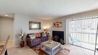 Located at 8755 Jenny Lind St in North Charleston, SC, this single-floor, 2-bedroom, 2-bathroom residence offers a functional and comfortable layout across a well-utilized footprint. The living room serves as the heart of the home, featuring a fireplace, soft carpet flooring, and a sliding glass door that opens to an outdoor area, allowing natural light to fill the space. The kitchen connects seamlessly to the living and dining areas via a pass-through counter with a light stone surface, offering an open feel while maintaining a defined cooking space with white cabinetry and appliances. The adjacent dining area comfortably accommodates a full dining set and flows naturally between the kitchen and living room. The primary bedroom is a generously sized retreat with carpeted floors, a window for natural light, and a textured ceiling. The second bedroom offers flexible use as a guest or additional room. Both bathrooms are well-appointed, with one featuring a full tub-shower combination with tile surround. Additional highlights include two closets for ample storage, a dedicated in-unit laundry area with full-size washer and dryer hookups and overhead shelving, and a textured ceiling throughout that adds a classic residential character to the home.