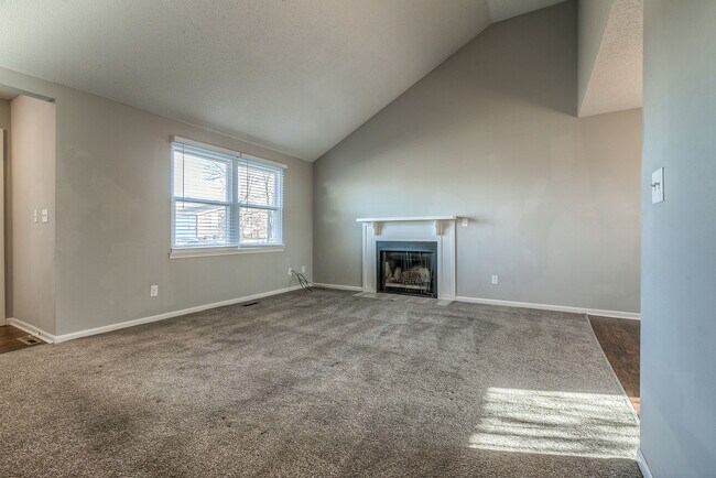 Sala de estar con techos abovedados, mucha luz natural y chimenea. - 13749 W 62nd St