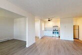 Located at 827 NE 99th Ave in Portland, Oregon, this two-bedroom, one-bathroom home offers a practical and well-organized single-floor layout. The combined living and kitchen area forms the heart of the home, where hardwood-style flooring flows throughout. The living room benefits from natural light streaming through a large sliding glass door fitted with vertical blinds, which opens to an outdoor balcony area. A baseboard heating system runs along the walls, ensuring year-round comfort. The kitchen is thoughtfully equipped with crisp white cabinetry, stainless steel appliances including a range, dishwasher, and refrigerator, and light countertops. A ceiling fan overhead and a window with blinds add to the kitchen's functionality and brightness. Both bedrooms are carpeted and feature neutral walls with baseboard heating, offering a cozy and quiet retreat. The primary bedroom provides a comfortable amount of space, while the second bedroom includes a window with natural light. The full bathroom is finished with white cabinetry, a vanity with sink, and light flooring. A hallway with closet and a dedicated entrance complete this efficiently designed home.