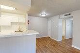 Located at 1239 Bay Area Blvd in Houston, TX 77058, this 2-bedroom, 2-bathroom single-floor unit offers a practical and well-organized layout across a comfortable footprint. The open-concept living and dining area features warm wood-look flooring and a textured ceiling, creating an inviting atmosphere filled with natural light from a sliding glass door that opens to a private patio with outdoor views. The galley-style kitchen is efficiently designed with white cabinetry lining both sides, a white appliance suite including a range and refrigerator, light countertops, and a peninsula with a sink that connects seamlessly to the living area. A dedicated pantry adds convenient storage. The two bedrooms are carpeted for comfort, each offering closet space — one with a built-in double-rod closet system. The spacious primary bedroom includes ample room and its own closet. Both bathrooms are clean and functional, featuring tub-shower combinations with white tile surrounds. A dedicated laundry closet with hookups provides in-unit convenience. The unit also includes five closets total throughout, maximizing storage. A hallway connects the private bedroom wing to the main living areas, contributing to a clear and efficient floor plan.