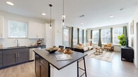 Located on Doctor Walter S. Davis Boulevard in Nashville, TN, this well-appointed 2-bedroom, 2-bathroom residence offers a thoughtfully designed single-floor layout. The welcoming entrance opens to a light-filled hallway with light wood-style flooring that flows throughout the main living areas. The open-concept kitchen, dining, and living space serves as the heart of the home, featuring a two-tone kitchen with crisp white upper cabinetry and gray lower cabinets, dark countertops, a subway tile backsplash, stainless steel appliances, and a center island with seating. Pendant lighting accents the kitchen, while large windows bathe the living area in natural light with views of the Nashville skyline. The spacious primary bedroom offers plush carpeting, generous window coverage, a ceiling fan, and access to a well-sized walk-in closet with built-in shelving. The second bedroom is equally comfortable. Both bathrooms are finished with white cabinetry and dark countertops, with one featuring a full soaking tub and shower. Additional highlights include a dedicated laundry area, utility room, three closets providing ample storage, and a clean, contemporary aesthetic throughout with neutral tones and modern fixtures.