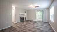 Located at 3900 Arcadia Lane in Henrico, Virginia, this single-floor residence offers a well-designed layout with consistent wood-look flooring throughout and a neutral color palette that creates a clean, cohesive aesthetic. The open living area serves as the heart of the home, featuring a ceiling fan with light fixture, a wood-burning fireplace with a classic white mantel, and sliding glass doors leading to a private balcony. Natural light flows in through multiple windows fitted with blinds, enhancing the bright and airy atmosphere. The kitchen is thoughtfully appointed with white shaker-style cabinetry, granite countertops, a white subway tile backsplash, and stainless steel appliances including a range, over-the-range microwave, and refrigerator. The bedrooms are generously proportioned, each with wood-look flooring, ample natural light, and access to closet space. The bathrooms are finished with wood-look tile flooring, white vanities, and full tub-shower combinations with brushed nickel hardware and towel bars. A textured ceiling is present throughout much of the space, adding a subtle architectural detail. The overall layout, visible in the floorplan view, reflects a practical and comfortable single-level design.