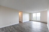 Located at 855 James St in Woodstock, Ontario, this 2-bedroom, 1-bathroom unit offers a straightforward and well-organized single-floor layout. Light grey laminate flooring runs throughout the space, giving it a cohesive and modern feel. The interior is finished in neutral, warm-white tones that reflect natural light and contribute to an open, airy atmosphere.

The kitchen is positioned near the entry and features white cabinetry, a stainless steel electric range, and a practical overhead exhaust fan — a functional space designed for everyday use. A hallway connects the main living areas to the bedrooms and bathroom, providing an efficient flow throughout the unit.

Both bedrooms are comfortably sized, with large windows that bring in generous natural light and offer views of the surrounding neighbourhood. Baseboard heating units are present in each bedroom, ensuring year-round comfort. The primary bedroom benefits from a sliding-door closet that maximizes storage, while the second bedroom is a clean, versatile space. A dedicated closet provides additional storage within the unit.

The bathroom is finished with large-format light stone-effect wall tiles surrounding a full-sized soaker tub with an overhead shower, lending a clean and polished look. Overall, this unit presents a tidy, neutral canvas with practical features throughout.