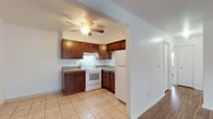 This single-floor residence at 6000 Jaycox Rd in North Ridgeville, Ohio offers a practical and well-organized layout across its living spaces. The kitchen is designed for efficiency, featuring rich dark-toned cabinetry with ample upper and lower storage, granite-patterned countertops, a double-basin stainless steel sink, and white appliances including a coil-burner electric range and a full-sized refrigerator. An under-cabinet range hood and a ceiling fan with integrated lighting keep the space comfortable and well-ventilated. Light ceramic tile flooring runs throughout the kitchen, extending into the adjacent living area, which transitions to warm wood-tone laminate flooring. The living area is bright and open, benefiting from a large window that allows natural light to fill the room. A wall-mounted heating and cooling unit provides year-round climate control. The bedroom features neutral carpet, a window with exterior views, and a dedicated closet equipped with a full-width hanging rod and upper shelf for organized storage. Clean white walls and simple, consistent finishes throughout the unit create a cohesive and move-in-ready environment suited for comfortable everyday living.