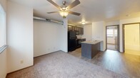 This single-floor unit offers a practical and modern layout designed for comfortable everyday living. The open-concept living and kitchen area serves as the heart of the space, where wood-look flooring flows seamlessly from the kitchen into the transition zone before giving way to plush carpeting in the living area. A ceiling fan overhead provides both airflow and ambient lighting, while exposed ductwork running along the ceiling adds an industrial accent to the otherwise clean, neutral interior.

The kitchen is outfitted with dark espresso cabinetry, light laminate countertops, and a full suite of black appliances, including a refrigerator, electric range, built-in microwave, and oven. A peninsula with a sink and additional counter space connects the kitchen to the living area, offering both functionality and an open sightline throughout.

The bedroom is generously proportioned, featuring soft carpeting, vaulted ceiling details, and a walk-in closet complete with a hanging rod and additional storage space. The bathroom is clean and functional, featuring a full tub-shower combination with a white surround, tile-look flooring, and simple chrome fixtures. In-unit laundry is also available, adding everyday convenience to this well-organized space.